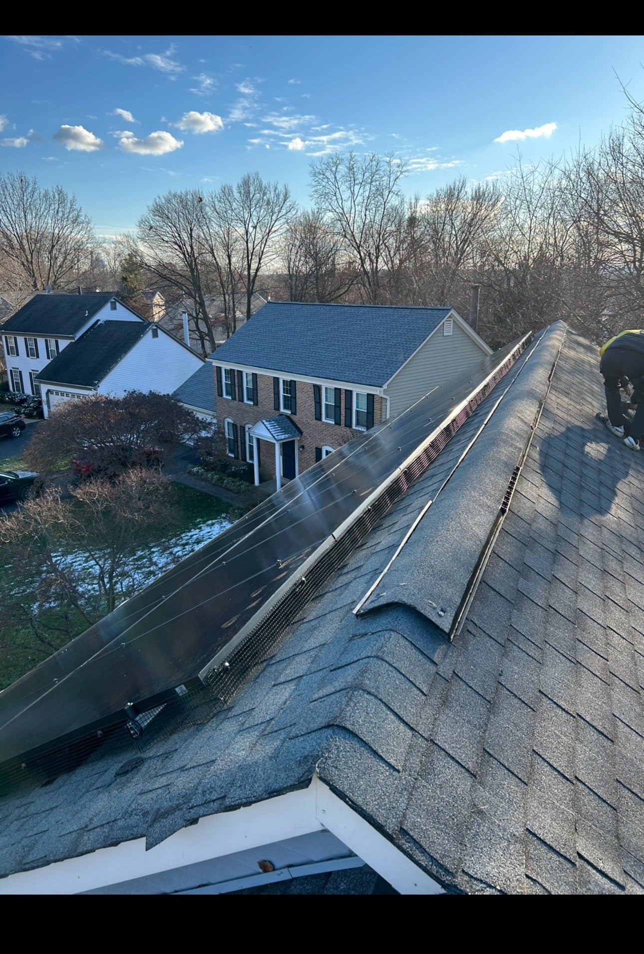 Technician securing critter guard mesh around solar panels in Virginia.