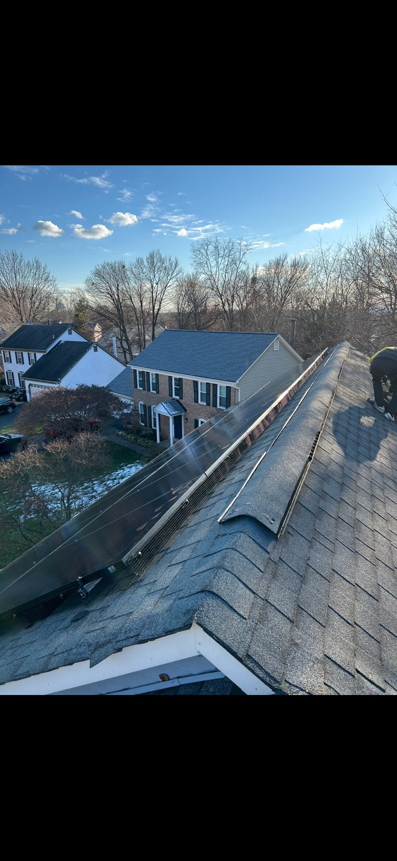 Technician securing critter guard mesh around solar panels in Virginia.